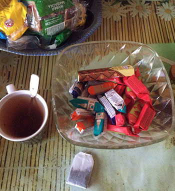 пакетик чая, кружка и ваза с конфетами